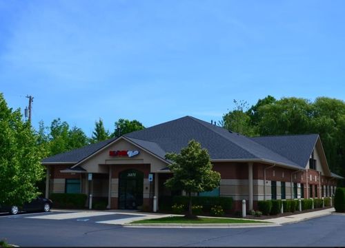 A single-story commercial building with a brick and stone facade, multiple windows, and a black roof