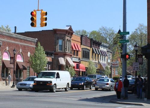 The image shows a street in Downtown South Lyon, Michigan, with cars and pedestrians