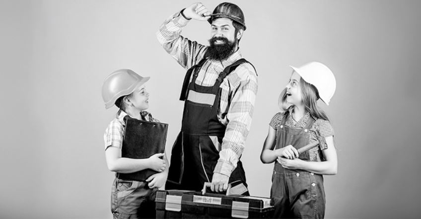 Three people in construction attire with tools, engaged in a task or discussion