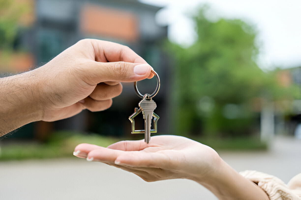 One hand handing a key to another person's hand