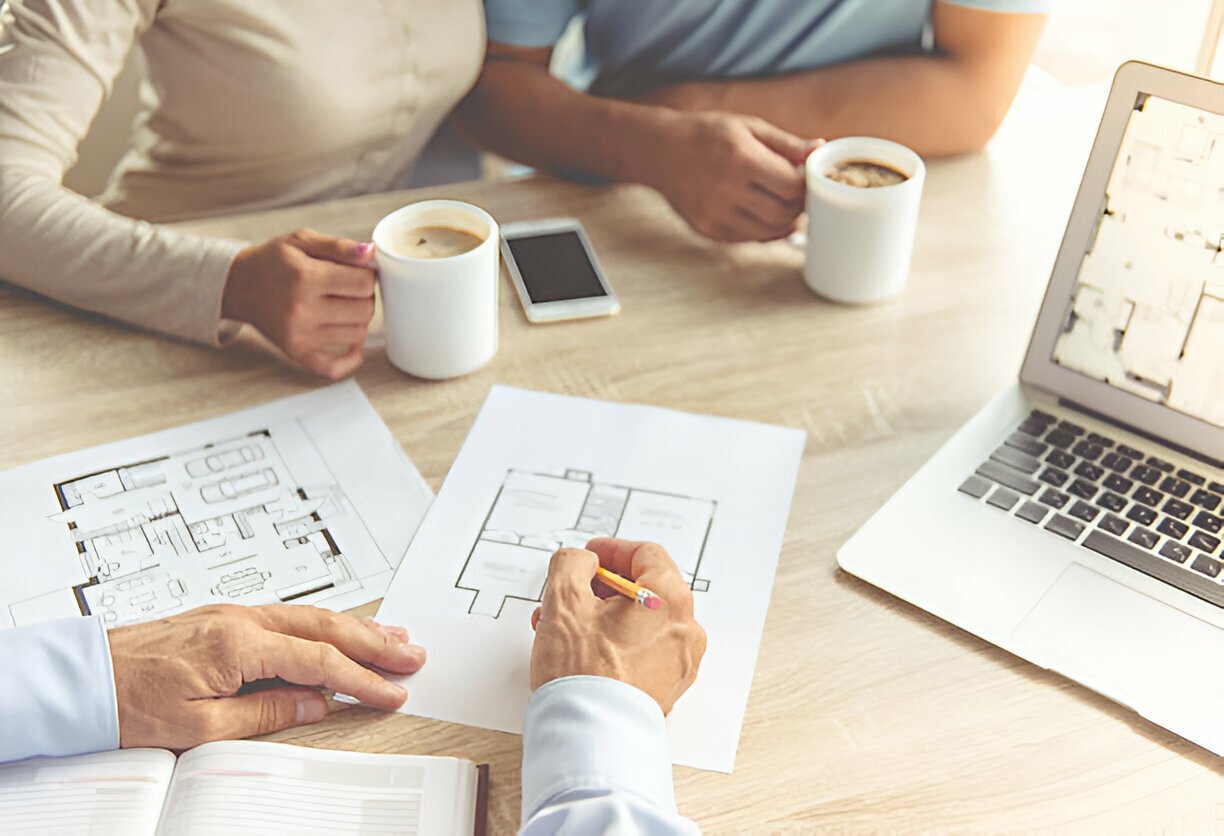 2D architectural plan displayed on a chart with two people engaged in discussion beside it