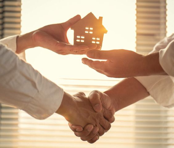 Handshake with one hand while the other hand is transferring a miniature house model