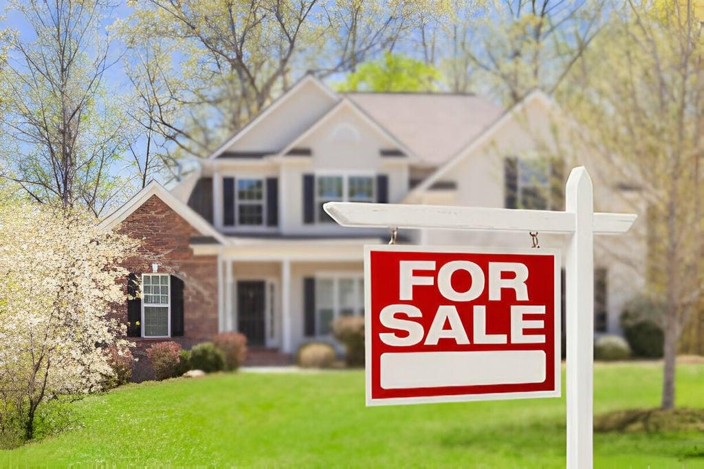 house with a "FOR SALE" sign in the front yard