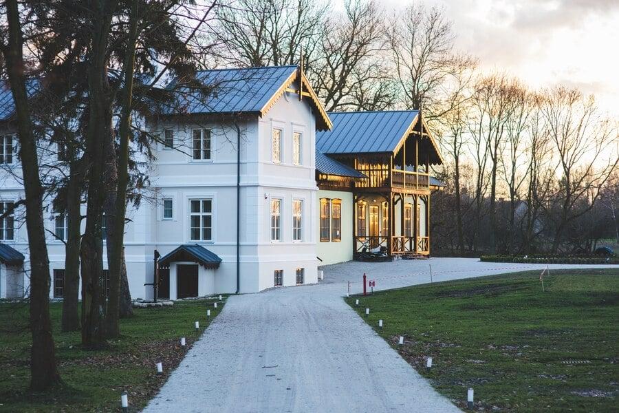 house has multiple windows and is surrounded by trees and a grassy area