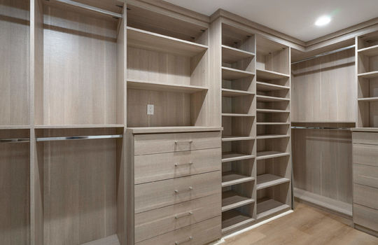 Primary Closet With California Closet Built-ins and a Floor Safe