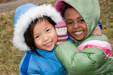 Two preschoolers in their coats having fun outdoors (shallow dof)