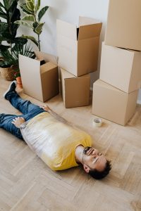 A man All wrapped up and cardboard boxes to his side