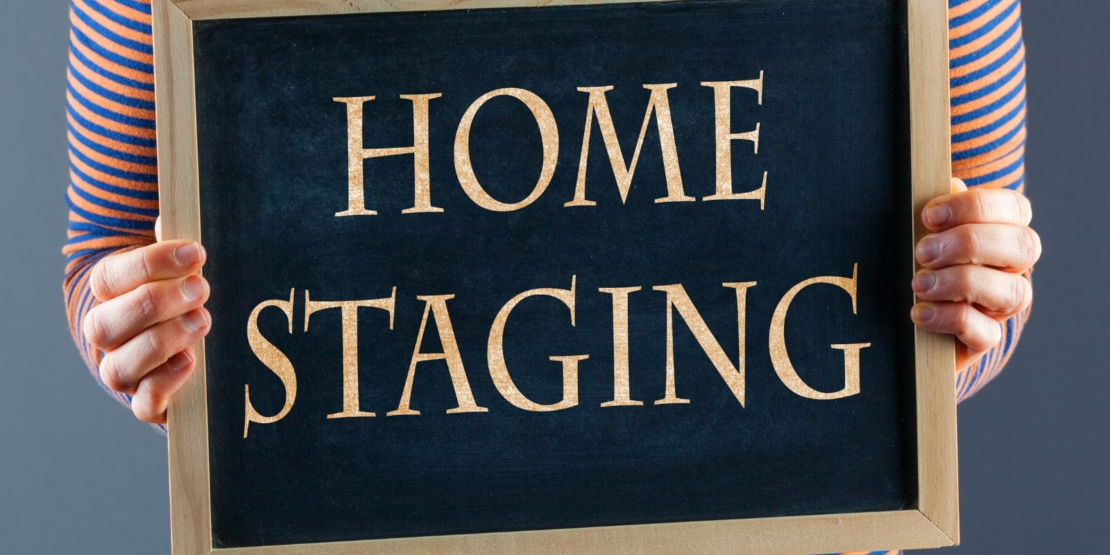 Woman holding a small blackboard that has the words "Home Staging" on it