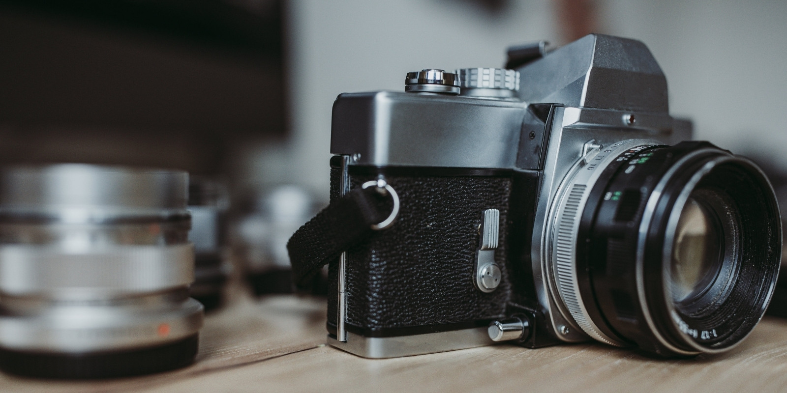 Old camera sitting on a table next to a lense