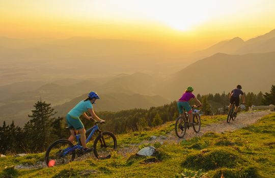 LENS FLARE: Four young travelers ride their mountain bikes downhill at sunrise.