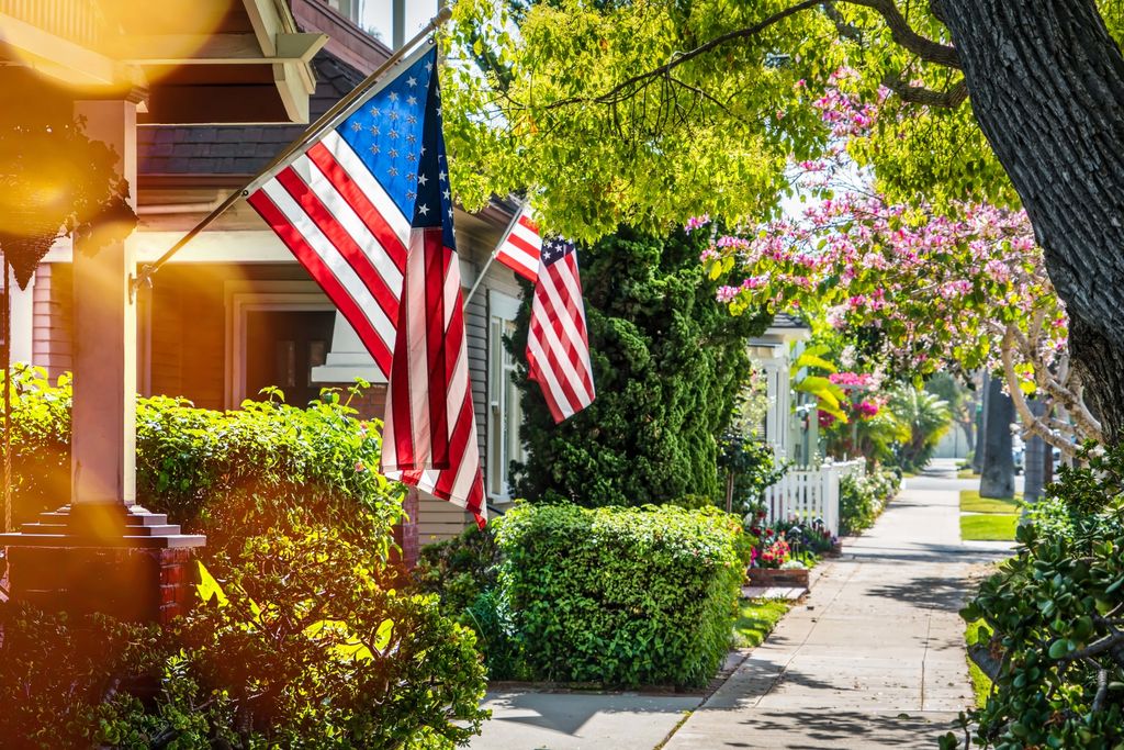 American street with flags on each home and a long sidewalk