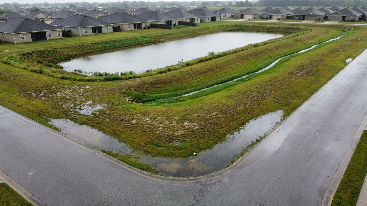 Neighborhood retention pond and streets with standing water after rain, for a post on flood insurance outside a mapped flood zone