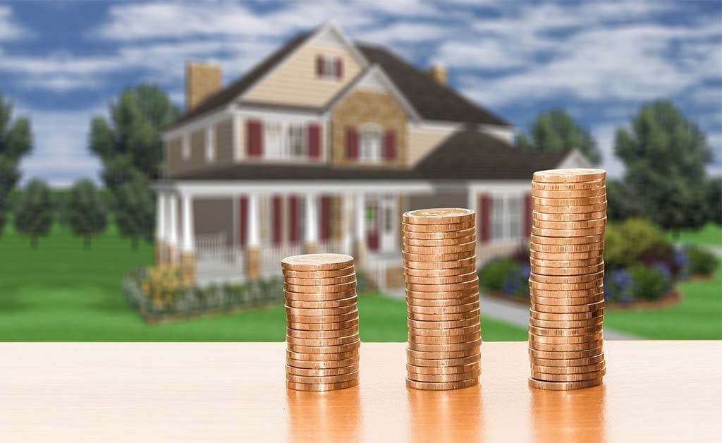 Saving for a mortgage downpayment as a renter. pennies stacked in front of a beautiful home.