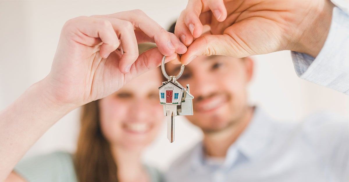 Man and woman holding keys to their new home.