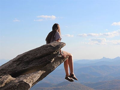 Girl sitting on the edge of the cliff at Rough Ridge in Boone, NC.