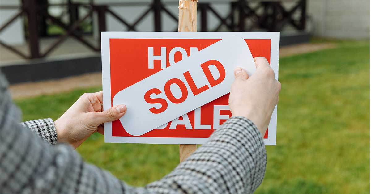 Realtor placing a sold sticker on a sign for a home that sold during a real estate bidding war in Boone, NC