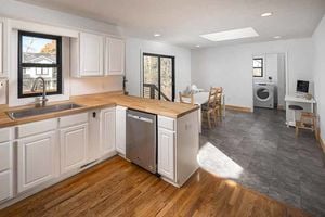 a decluttered white kitchen with hardwood floors and butcher block countertops and stainless steel dish washer