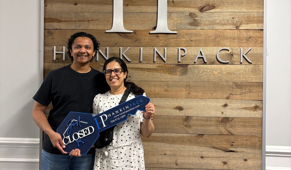 Mrinal and Darshan standing in front of their new home in Sedgefield Charlotte with Adrien Hebert from Stone Realty Group