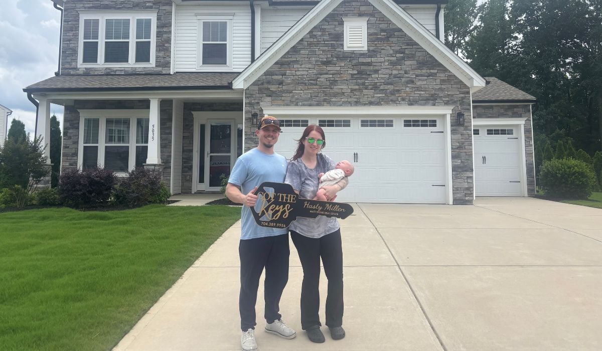 Brandon and Heather celebrating in front of their new Monroe, NC home after relocating with the help of Hasty Millen and Stone Realty Group
