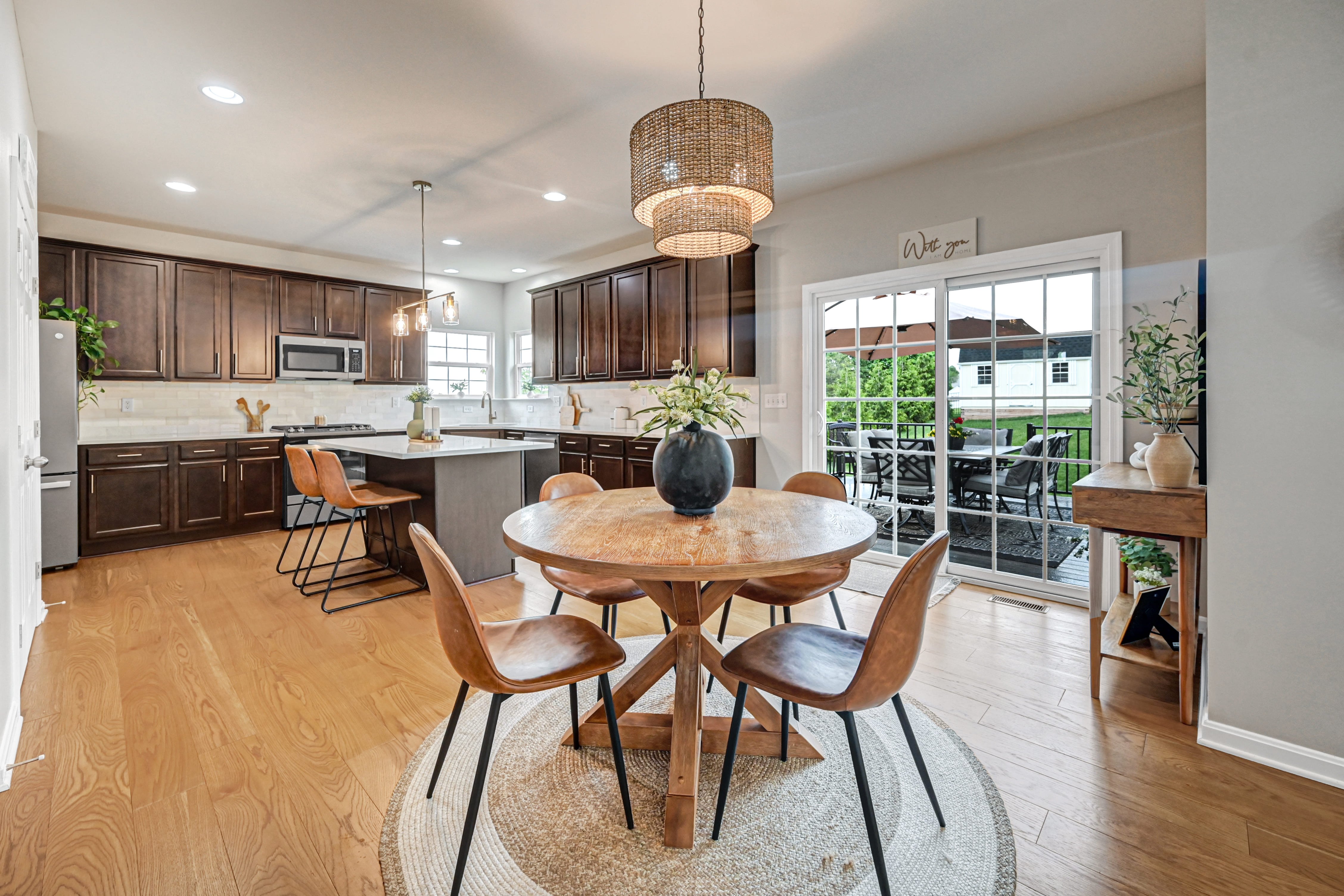 Beautiful kitchen and dining room combo. Circular wooden table with 4 chairs in dining area that opens to lovely dark cabinets, full kitchen island with 2 barstools, and sliding door to the back deck.