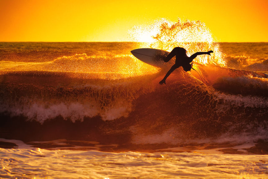 A person surfing at sunset.