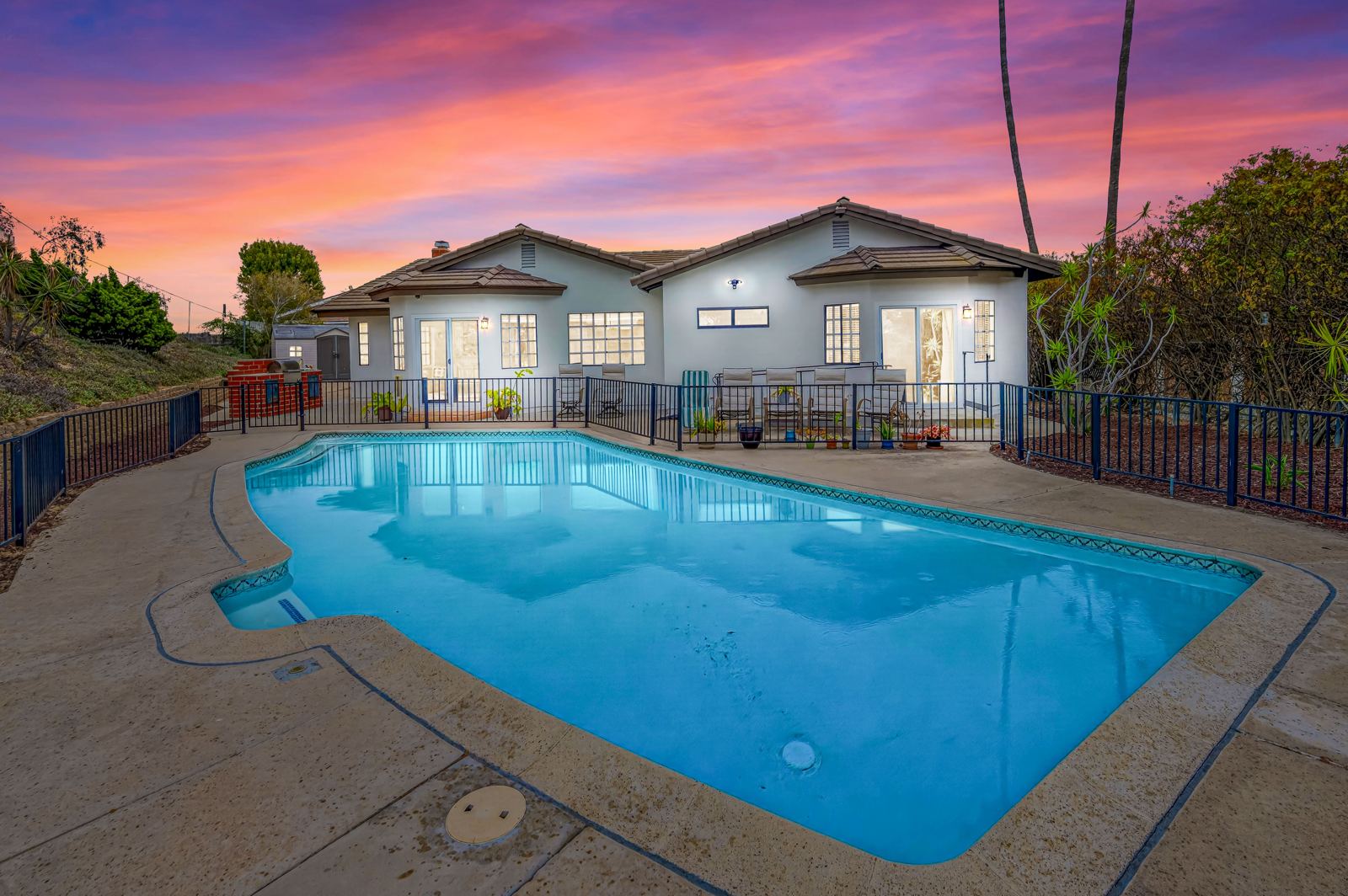 Backyard pool at dusk with the single-level home behind it