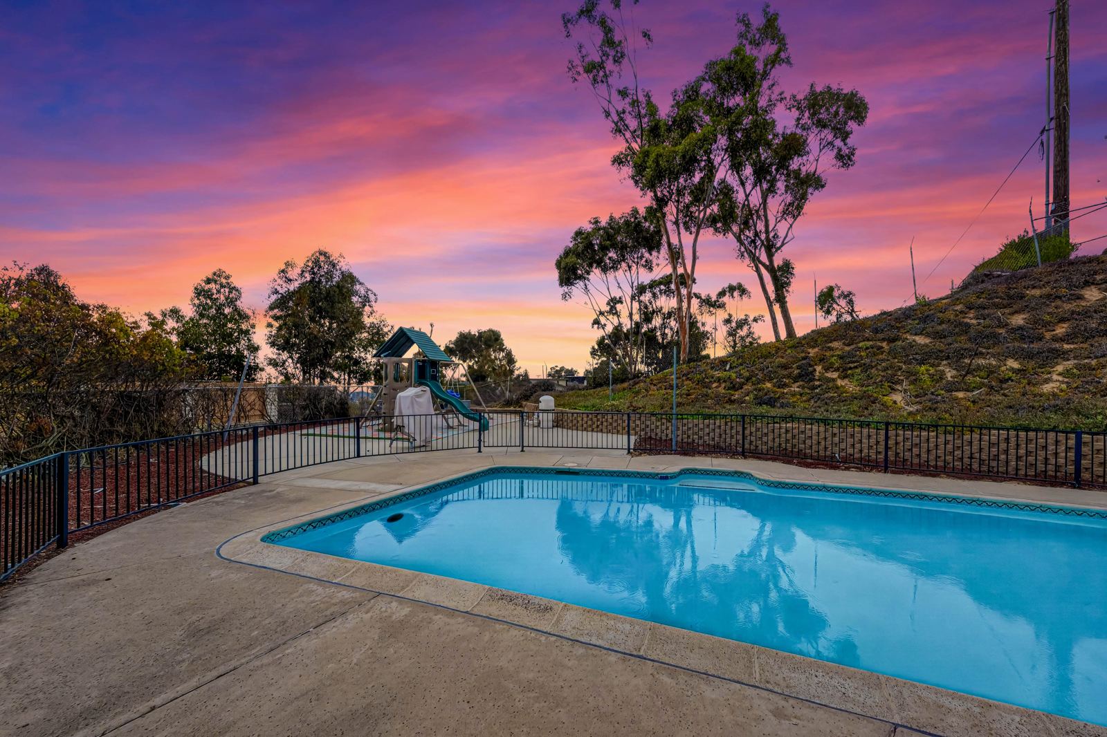 Pool deck at sunset with iron fencing
