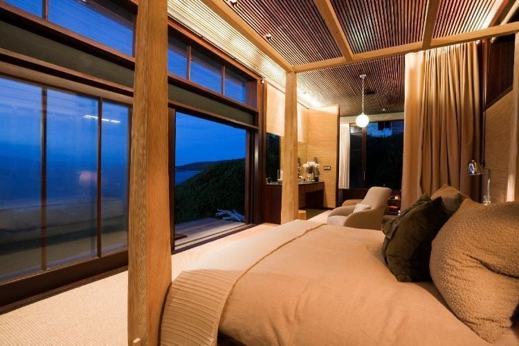 Bedroom of a luxury beach cottage with picture windows facing the sea.