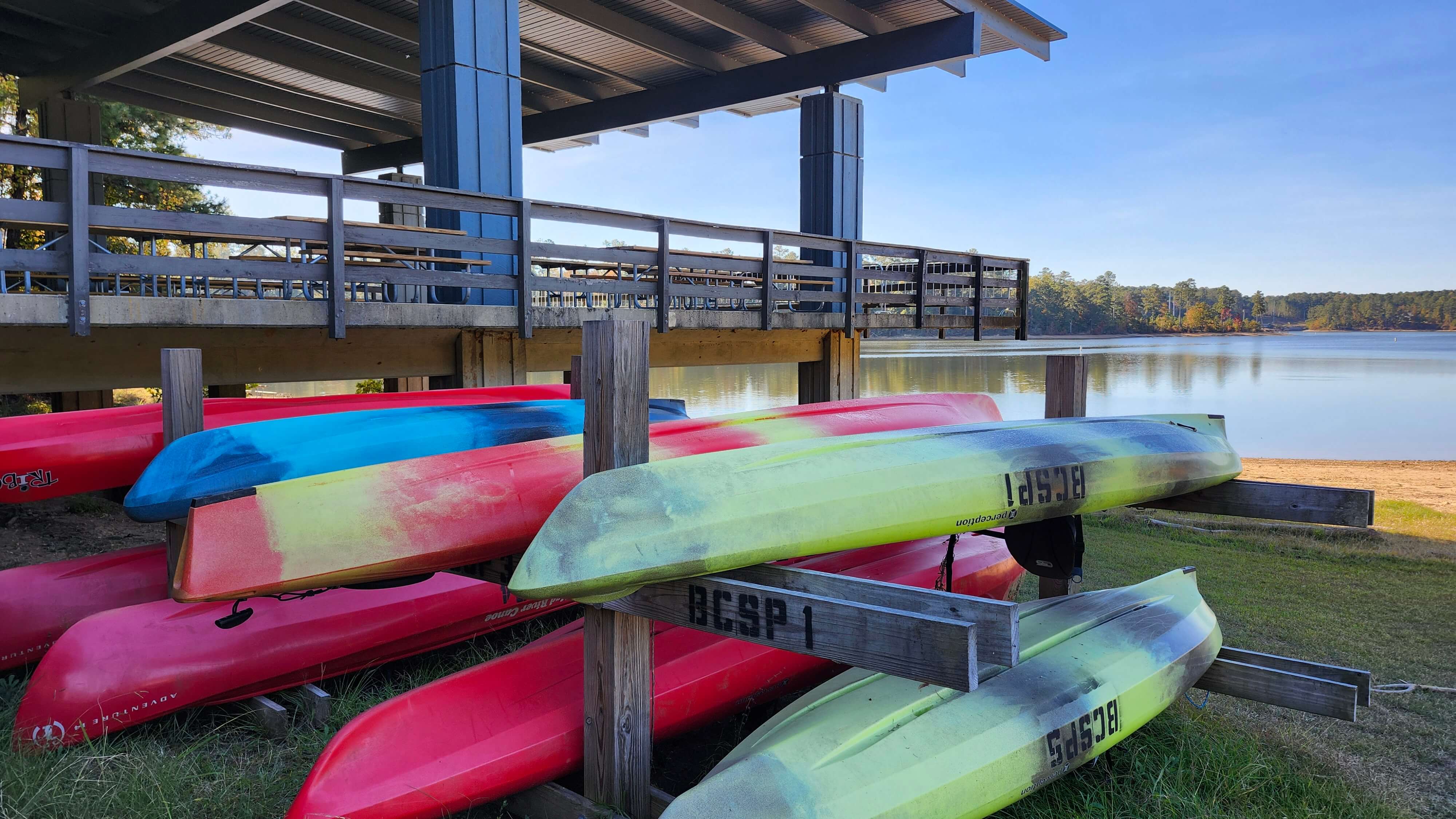 Colorful kayaks and stand up paddleboards neatly staged for rental on the shoreline