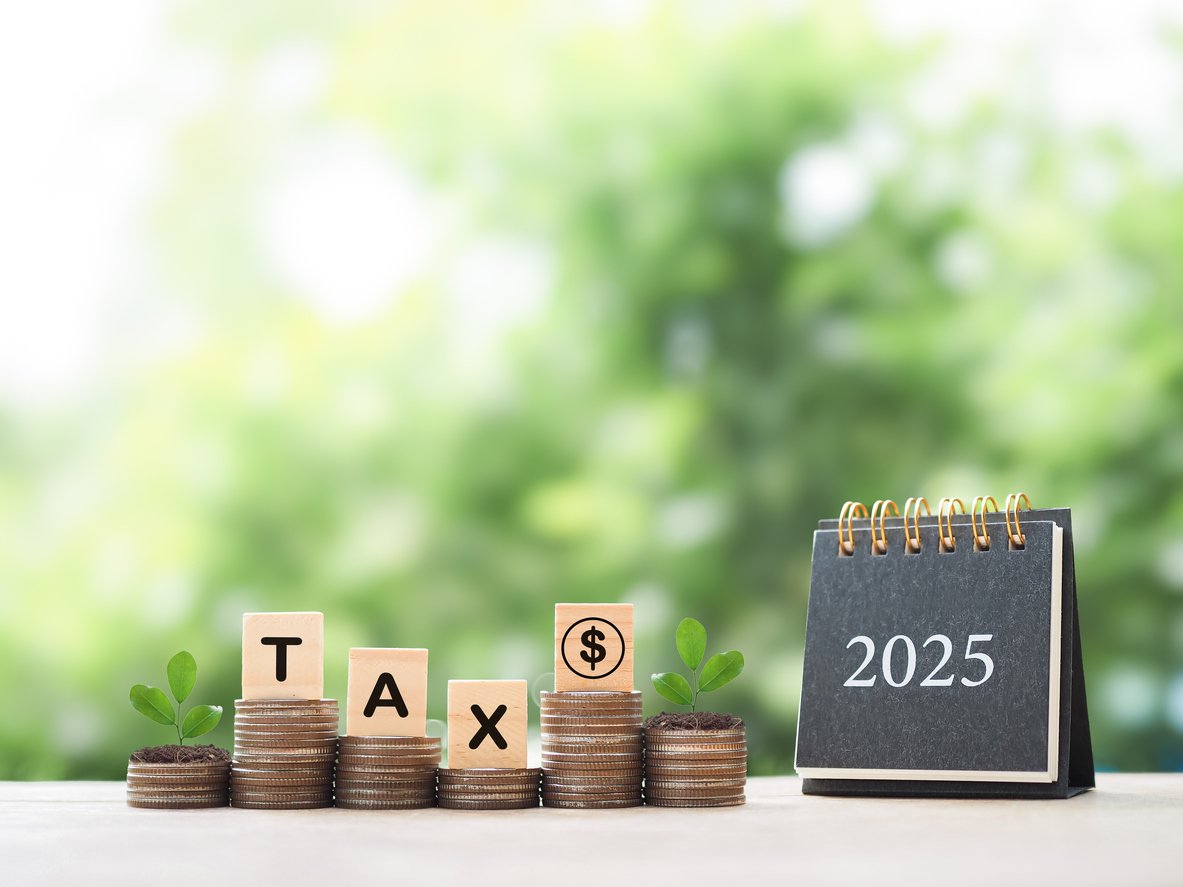 2025 desk calendar, Wooden blocks with the word TAX and plants growing up on stack of coins. The concept about saving money and manage time to paying tax in year 2025