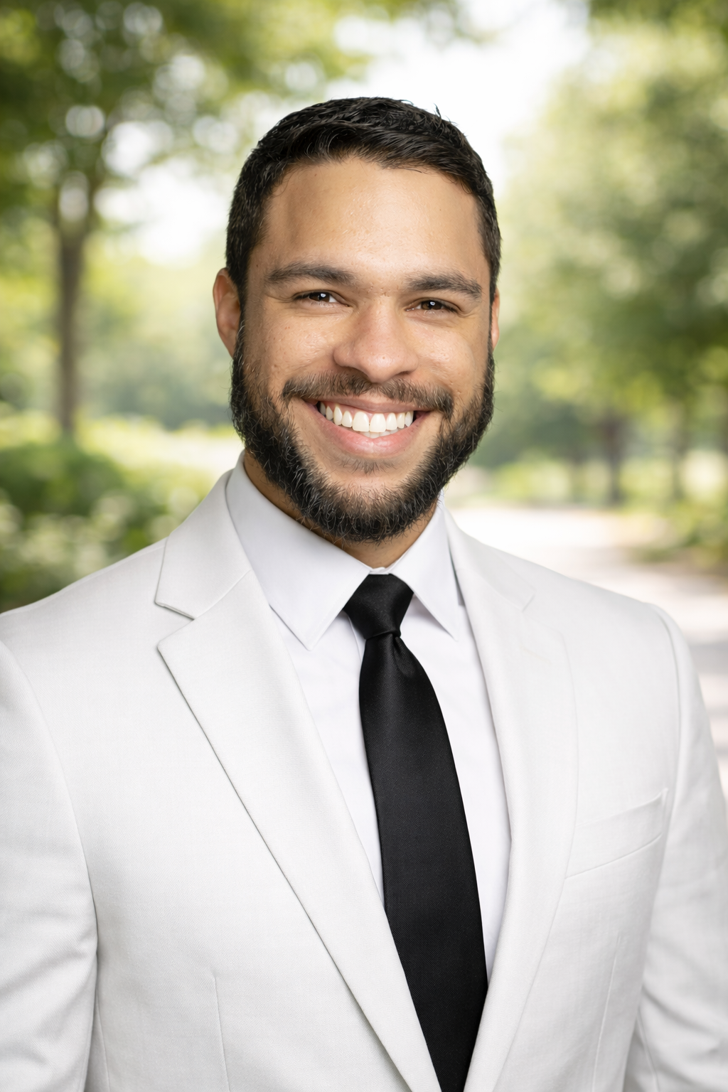 Andre Berry headshot in a park with a slightly blurred background.