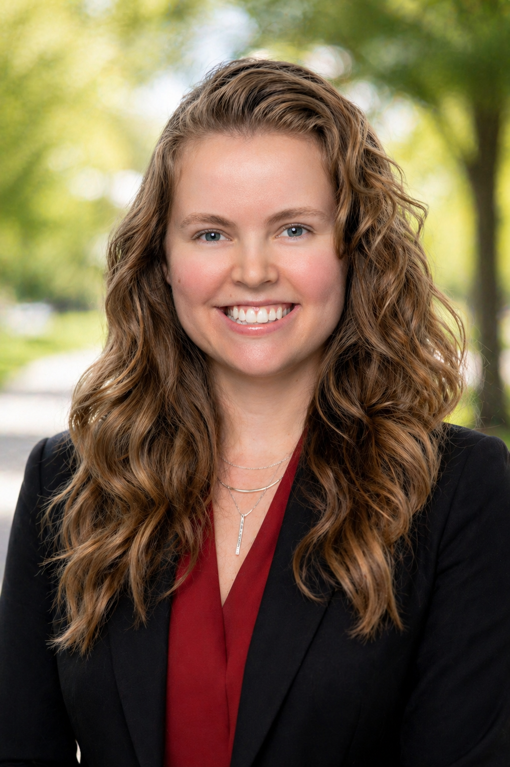 Cassondra Hyman headshot in a park with a slightly blurred background