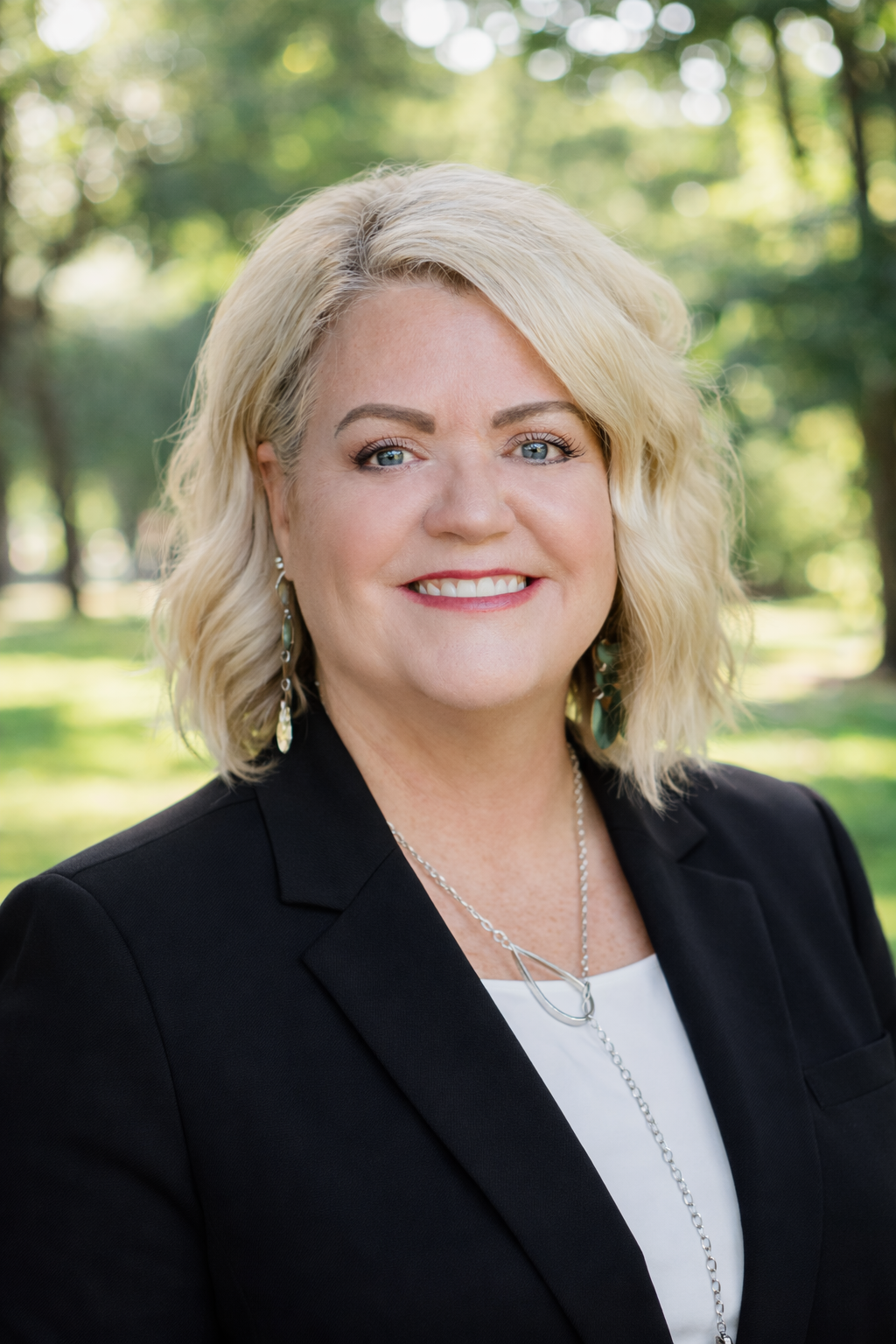 Amy Lemoine headshot in a park with a slightly blurred background.