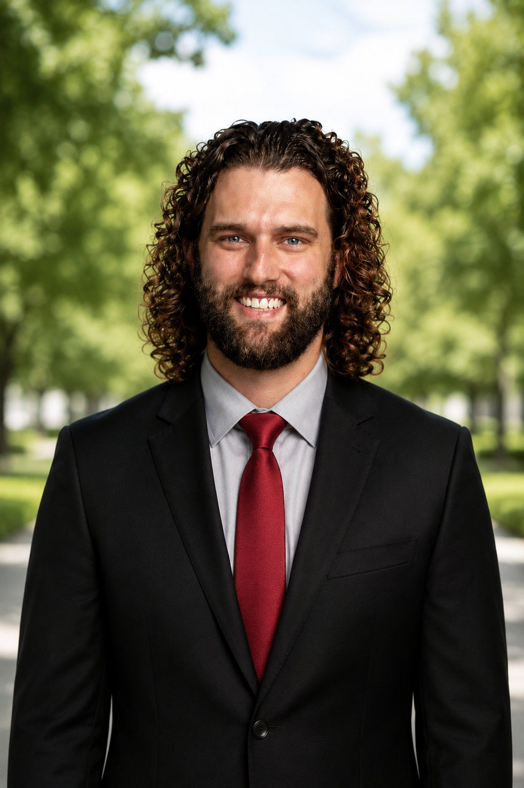 Kyle Davis Sims headshot in a park with a slightly blurred background
