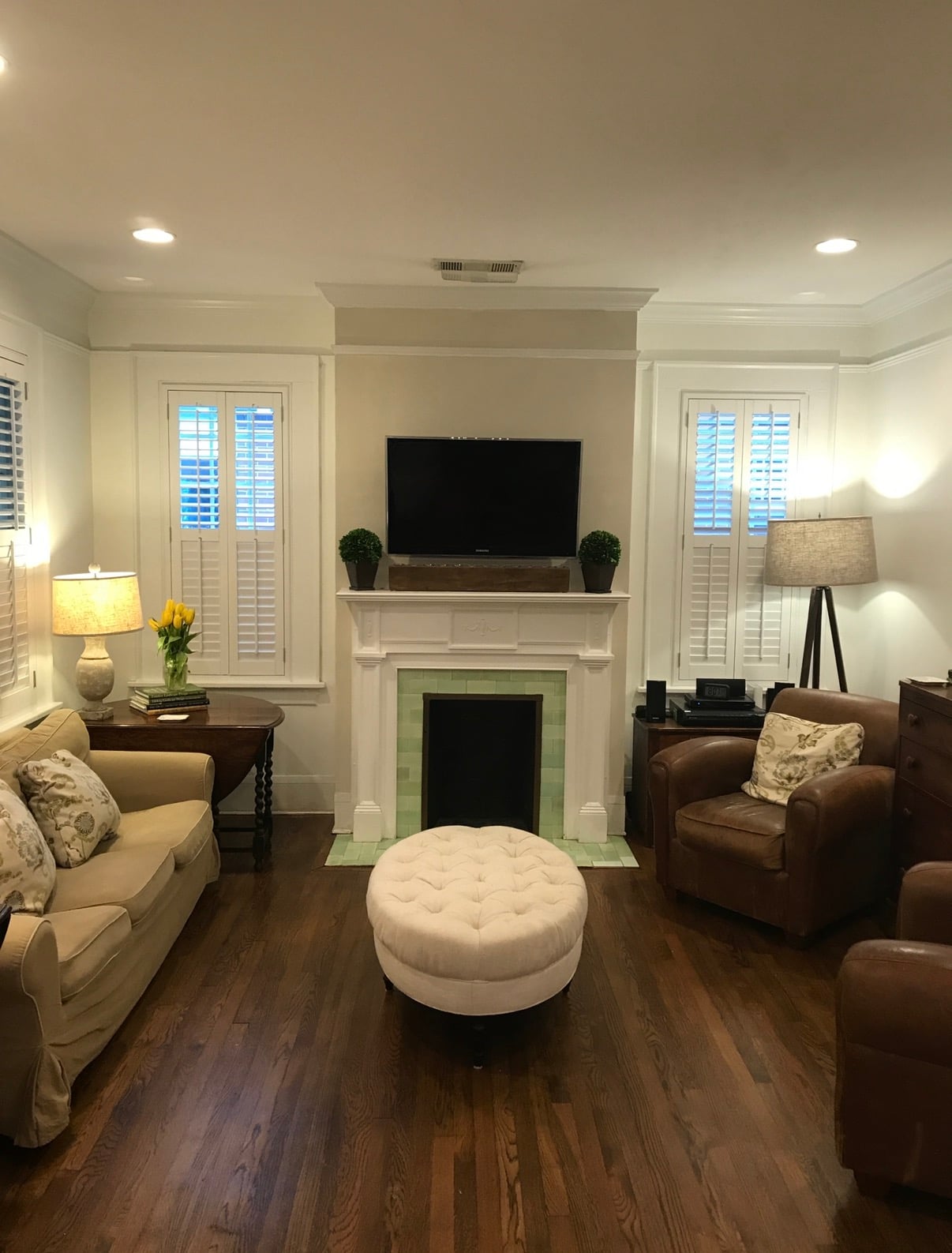Living room with original mantel, green tile fireplace surround, and hardwood floors in a historic Midtown Columbus home