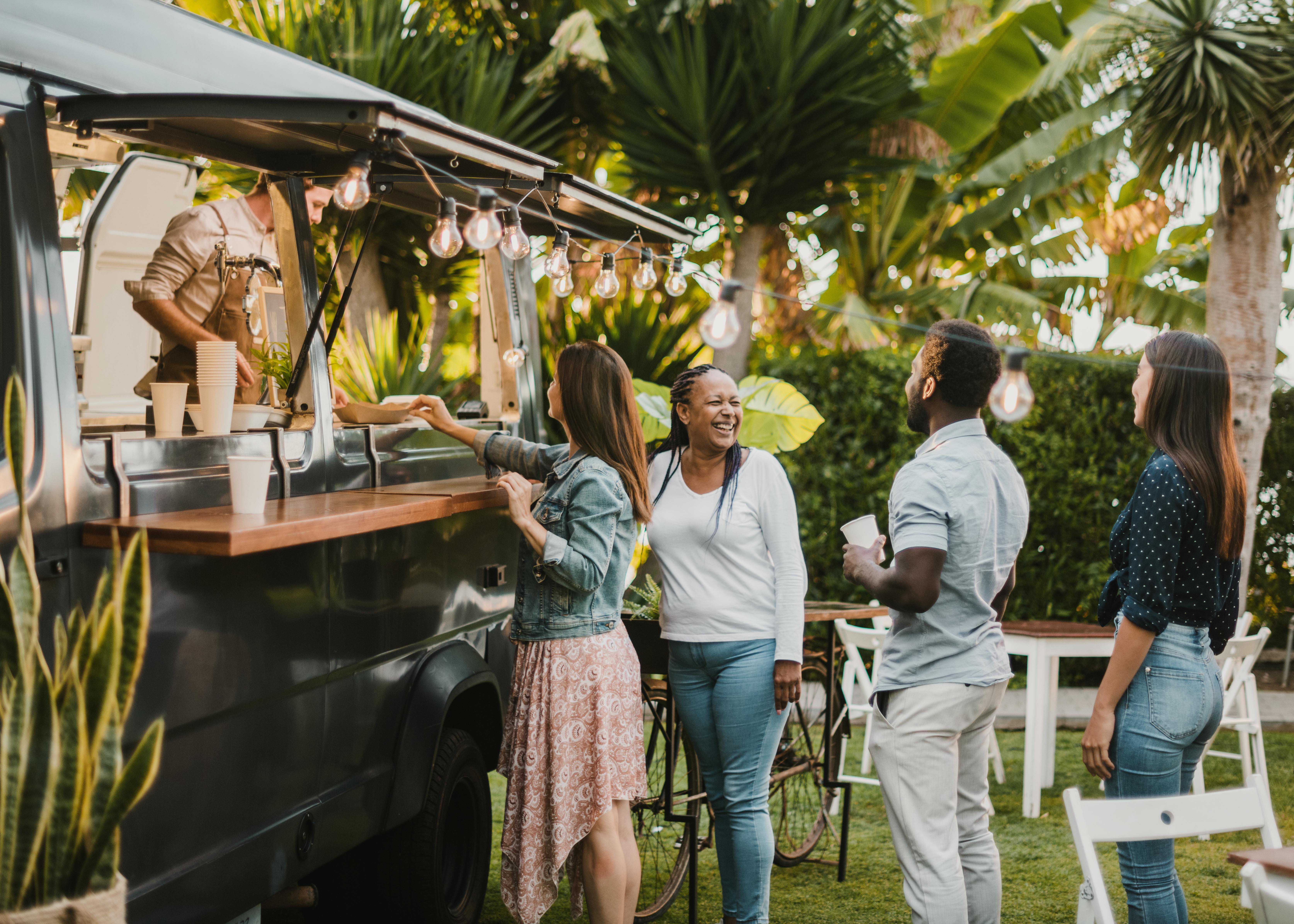 Multiracial friends talking near food truck in park