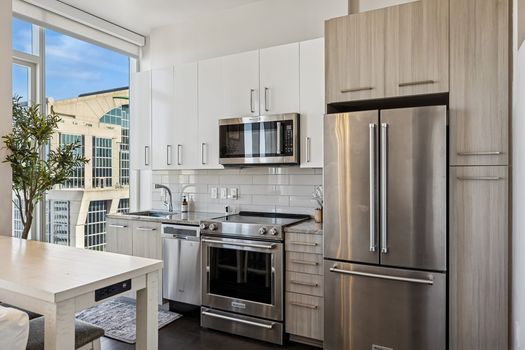 Kitchen interior at 505 Nashville unit 3302 on the 33rd floor with stainless steel appliances and floor to ceiling windows overlooking downtown Nashville and First Horizon Par