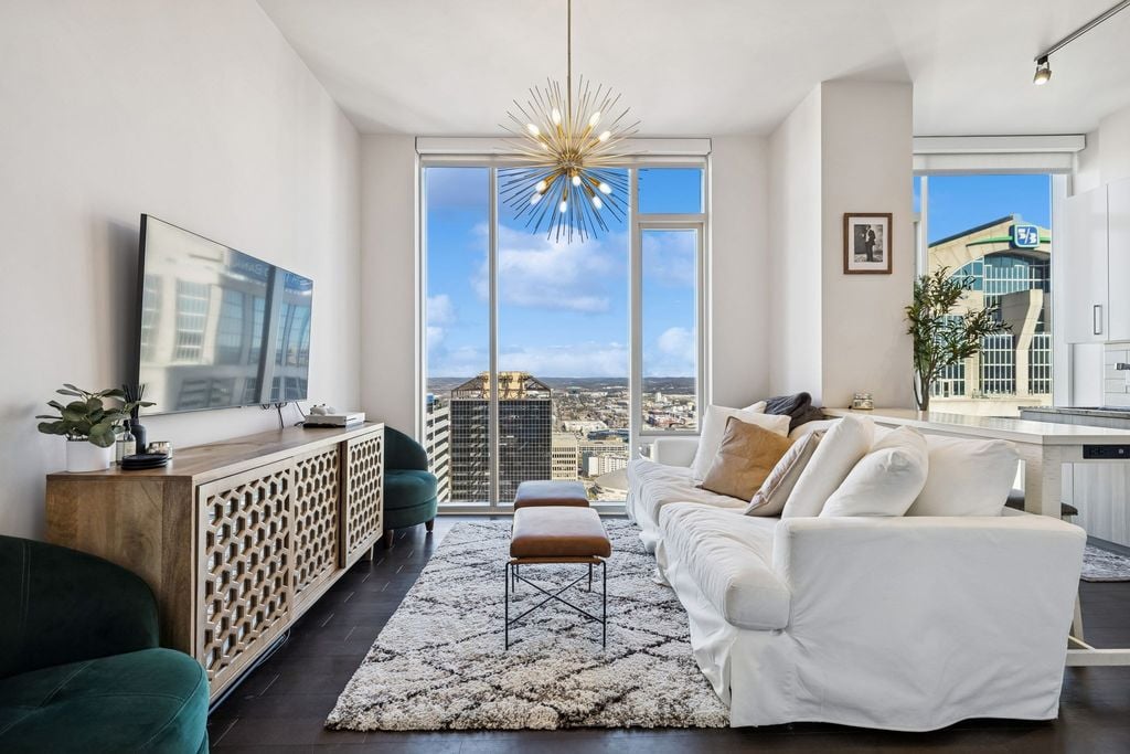 Living room interior at 505 Nashville unit 3302 on the 33rd floor with floor to ceiling windows and sweeping views of the downtown Nashville skyline and First Horizon Park