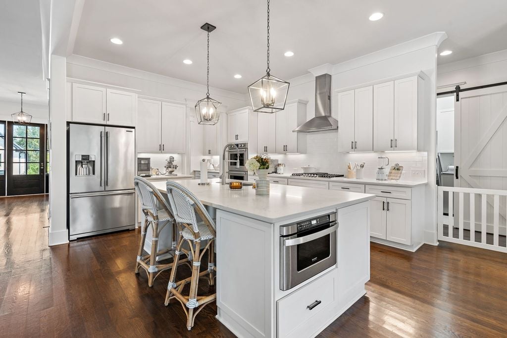 Open concept kitchen with white cabinetry, quartz island, hardwood floors, and pendant lighting in a Ladd Park home in Franklin TN 37064