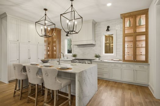 Chef's kitchen with stone waterfall island, glass-front oak cabinets, and Thermador appliances in 12 South Nashville new construction home