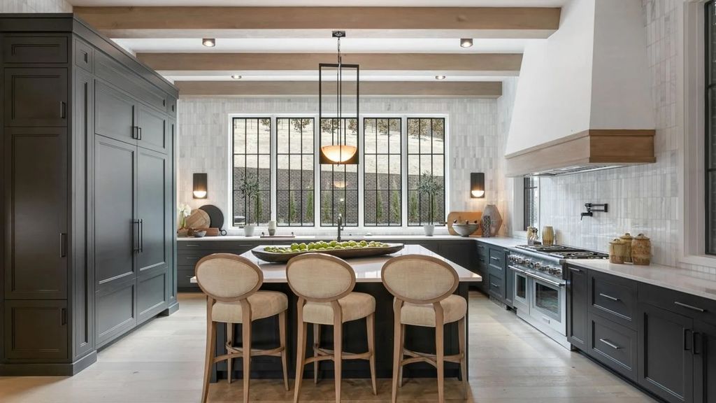 Luxury Nashville kitchen with dark cabinetry, exposed wood beams, marble tile backsplash, and designer island seating