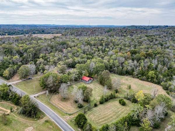 Aerial drone view of rural land and acreage in Middle Tennessee with red barn and open fields 