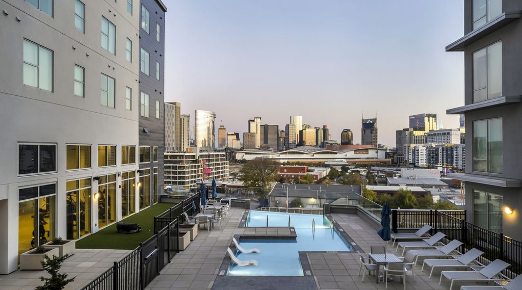 Rooftop pool and lounge deck at a Gulch Nashville condo building with the Downtown Nashville skyline at dusk