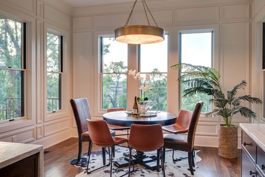 Dining area with paneled walls, designer brass chandelier, and treetop views in the new construction home at 3304 Love Cir, West End Nashville