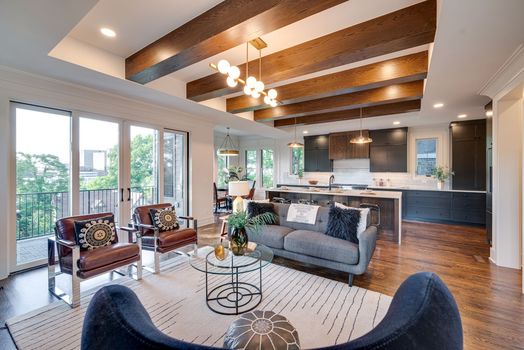 Open-concept living room and chef's kitchen with exposed wood beams and white oak flooring at 3304 Love Cir, Nashville TN 37212