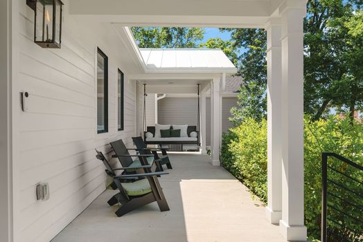 Covered front porch with a hanging swing and modern chairs at 1806 5th Ave N in Salemtown, Nashville