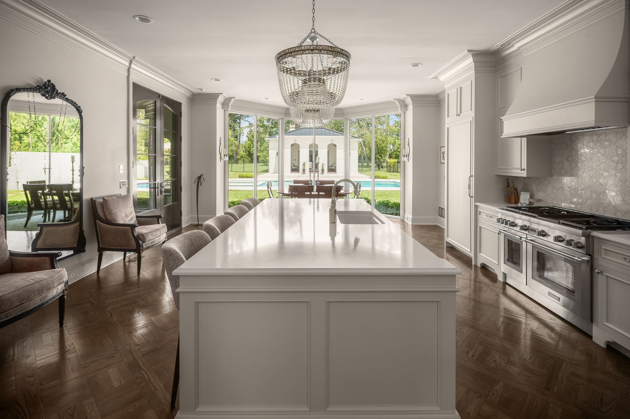 Chef's kitchen with parquet herringbone floors, crystal chandelier, and pool views at 4753 Post Road, Nashville