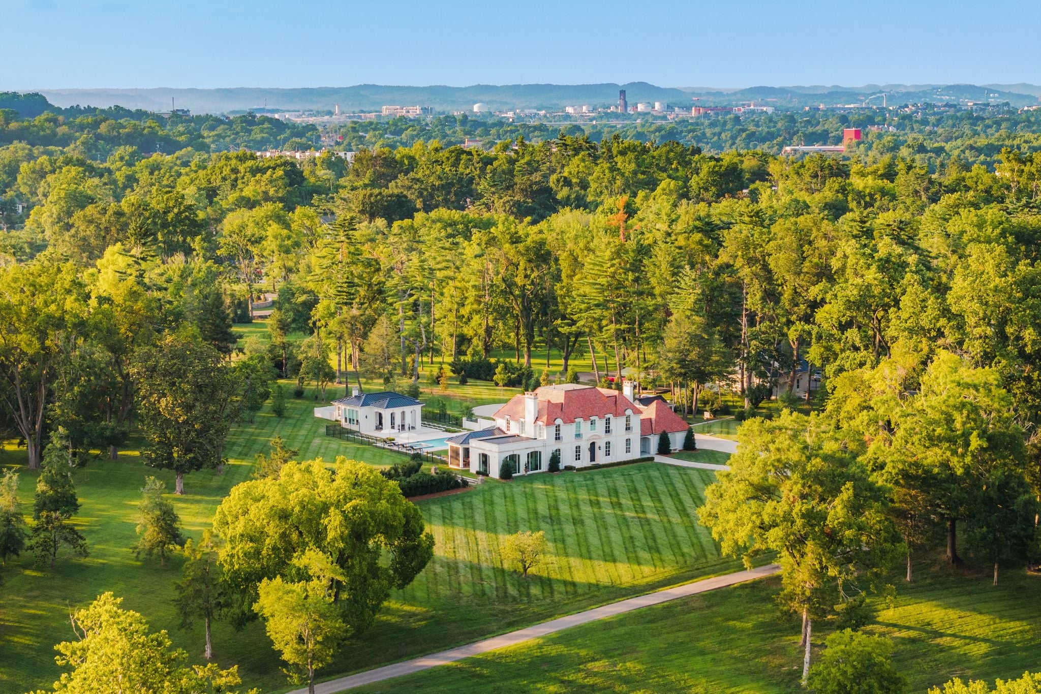 Daytime aerial of 4753 Post Road showing the white estate, Richland Creek and stone bridge, Hillwood Nashville