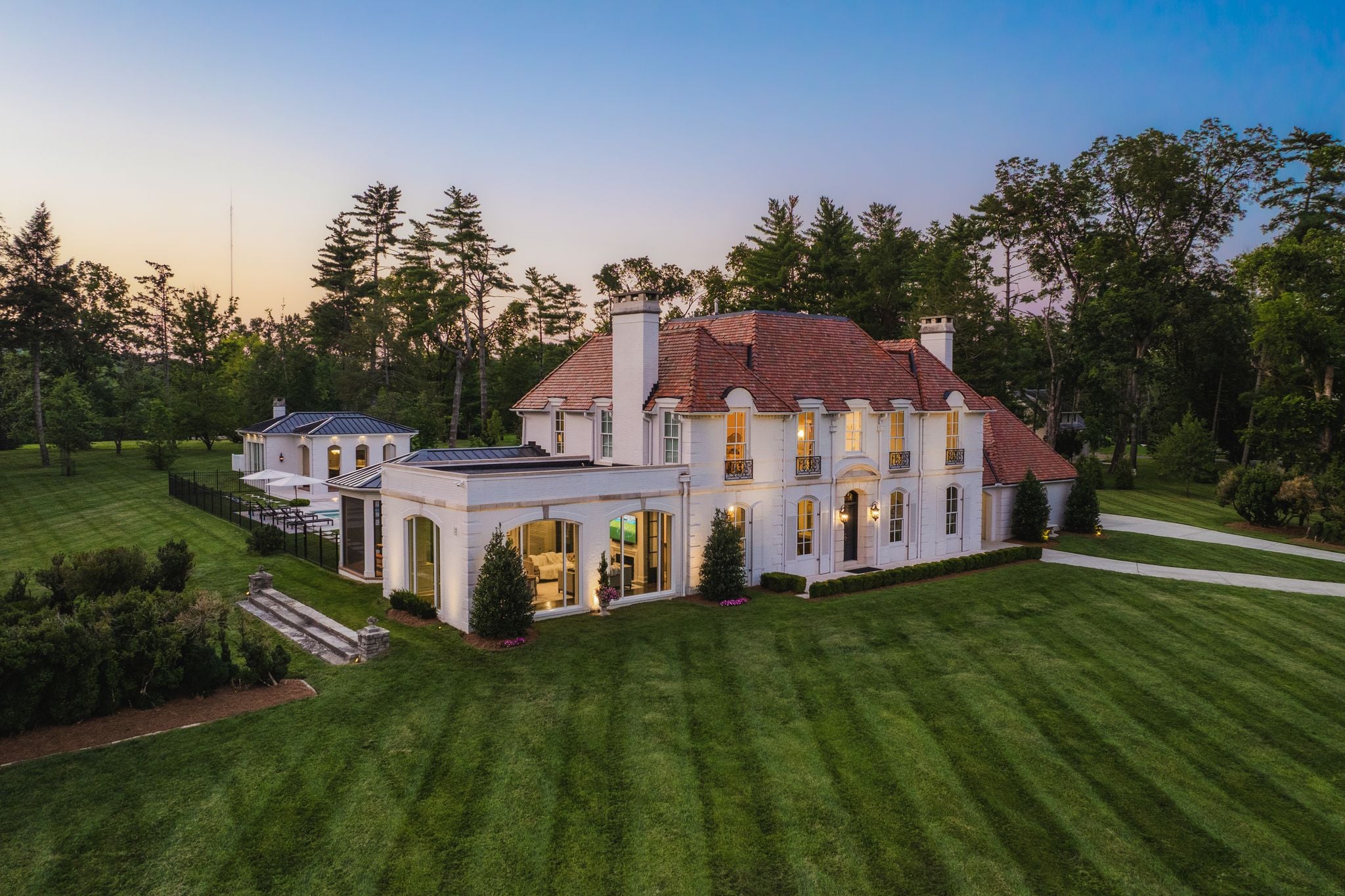 Twilight aerial of the white French-inspired estate at 4753 Post Road above Richland Creek in Hillwood, Nashville