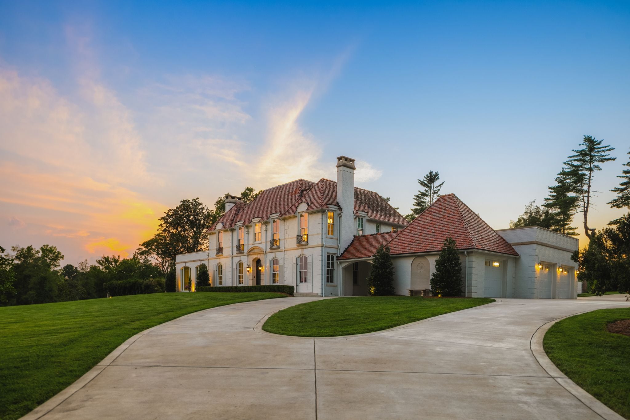 Twilight front elevation of the French-inspired residence at 4753 Post Road glowing, Hillwood Nashville
